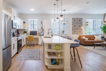 A kitchen and living room with white walls and hardwood floors